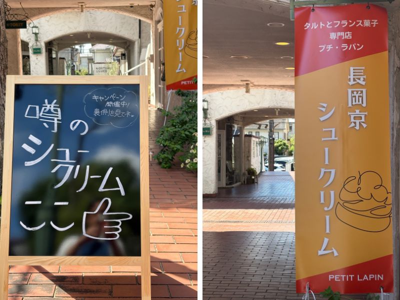 プチ・ラパン（PETIT LAPIN）の店舗入口。左側に青色の立て看板で「噂のシュークリームここ」とキャッチコピーと指差しアイコン、右側に橙色の柱看板に「長岡京シュークリーム」「タルトとフランス菓子専門店」の文字。アーチ型の通路入口が見える店舗外観