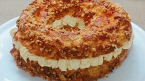 車輪形のシュー皮にプラリネ風味のバタークリームをたっぷり絞り、砕いたナッツをまぶしたパリ・ブレスト。断面にはクリームの層が美しく広がっている。